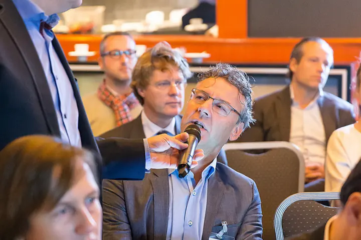 Gert-Jan Jansen houdt een deelnemer in de zaal de microfoon voor