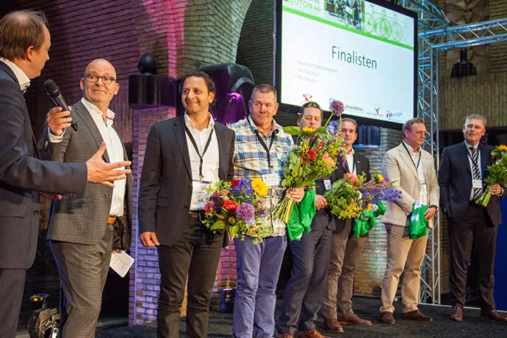 Gert-Jan Jansen op het podium met een groep mensen met bloemen