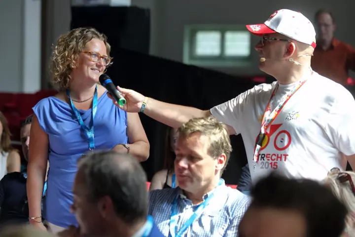 Een deelneemster spreekt in de microfoon tussen het publiek
