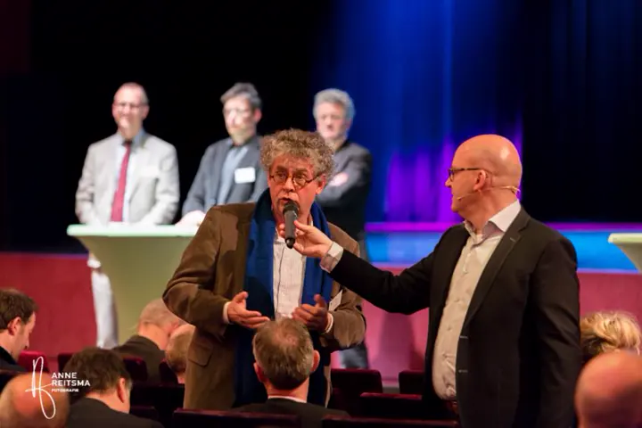 Gert-Jan Jansen houdt een gast in de zaal de microfoon voor