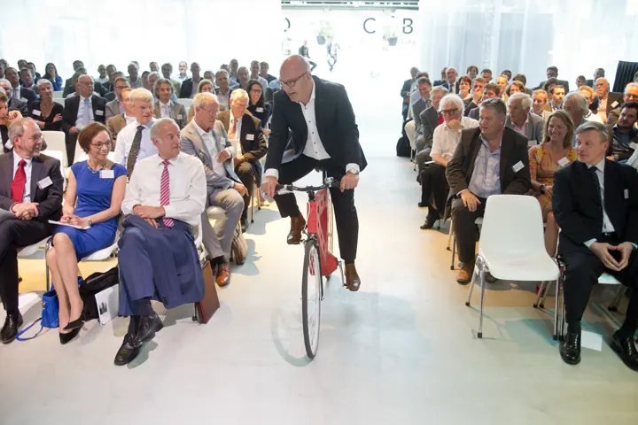 Gert-Jan Jansen fietst door het middenpad van een volle zaal